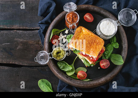 Low-Carb Gluten freie Cloud Brot vegetarischen Sandwich mit Avocado, Spinat, Feta-Käse, Tomaten und Pesto-sauce, serviert auf Lehm tr Stockfoto