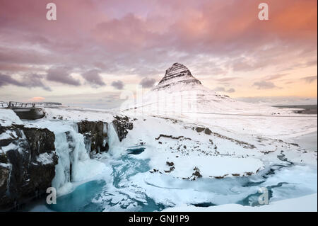 Winter-Sonnenaufgang über Kirkjufellsfoss Wasserfälle von Berg Kirkjufell oder Kirche, unterstützt Grundarfjoraur Snaefellsnes Stockfoto