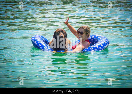 Frau und Schokolade Labrador Retriever Hund im Ozean auf float-Gerät Stockfoto