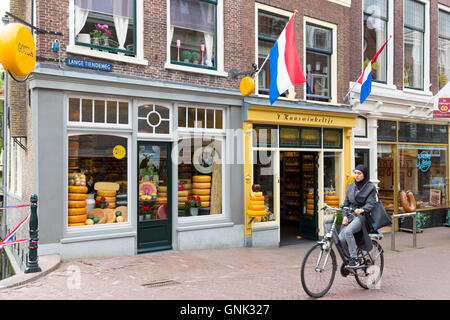 Frau trägt muslimischen Schleier Zyklen vorbei Käseladen ' t Kaaswinkeltje in Lange Tiendeweg in Gouda, Holland, Niederlande Stockfoto