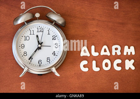 Ein Wecker mit den Worten "Wecker in kleinen Buchstaben geschrieben auf einem dunklen Hintergrund'. Stockfoto