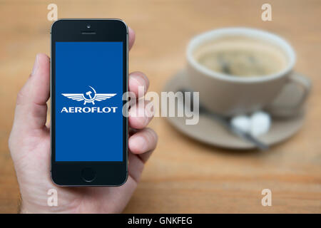 Ein Mann schaut auf seinem iPhone die Aeroflot-Logo anzeigt, während bei einer Tasse Kaffee (nur zur redaktionellen Verwendung) saß. Stockfoto