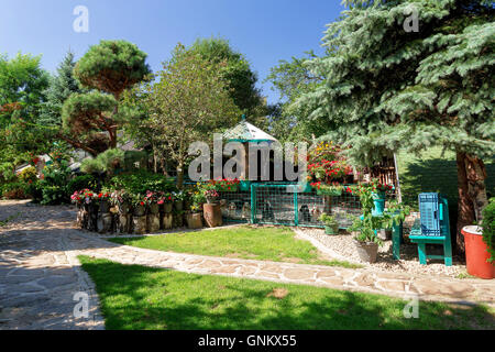 Hund Baby Gartenhaus mit Blumen auf Deckstation Hund. Sommer-Garten-Design mit Blumen in voller Blüte. Blauen Morgenhimmel. Rot Ne Stockfoto