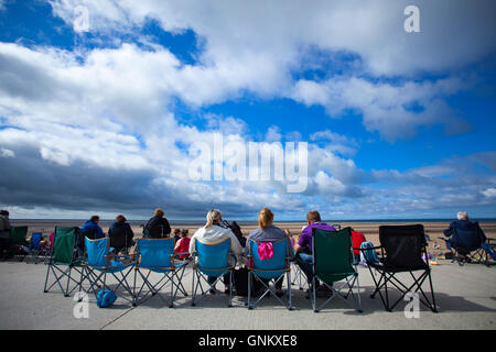 Zuschauer warten auf den nächsten Teil der Rhyl Air Show Ort whislt zu nehmen Wohnzimmer tun Strand Liegestühle auf der Promenade in den Himmel schauen, Rhyl Stockfoto