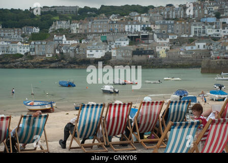 Liegestühle und Taschentücher in Hüte im Hafen von St. Ives, Cornwall gemacht. Stockfoto