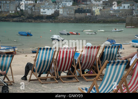 Liegestühle und Taschentücher in Hüte im Hafen von St. Ives, Cornwall gemacht. Stockfoto