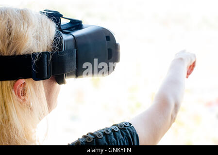 Geschäftsfrau mit virtual-Reality-Brille in einem städtischen Umfeld. Neue Technologie in Unternehmen (oder Architektur) Konzept. Stockfoto