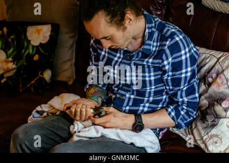 Mann mit Tattoos, die drei Wochen alten Baby-Eichhörnchen füttern Stockfoto