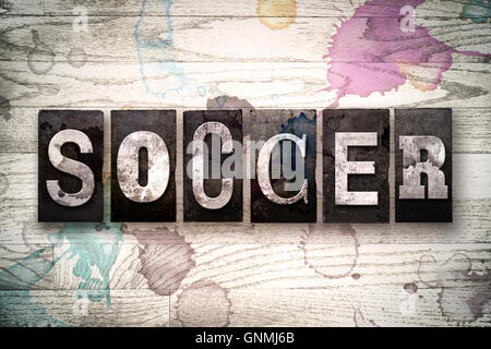 Das Wort "Fußball" in Vintage, schmutzige Metall Buchdruck Typ auf einem weiß getünchten hölzernen Hintergrund mit Tinte und Farbe Flecken geschrieben. Stockfoto