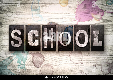 Das Wort "Schule" geschrieben in Vintage, schmutzige Metall Buchdruck Typ auf einem weiß getünchten hölzernen Hintergrund mit Tinte und Farbe Flecken. Stockfoto