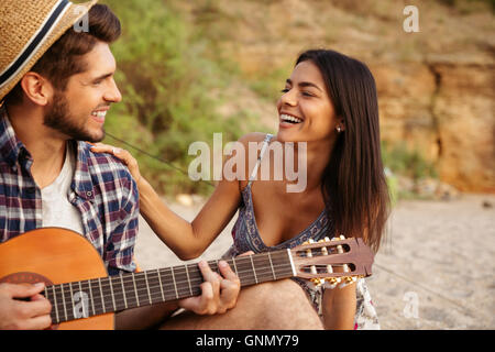 Porträt eines Mannes, Gitarre zu spielen, für seine Freundin sitzen am camping Zelt Stockfoto