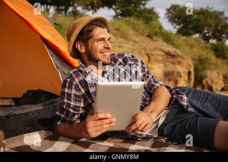 Glücklich schönen jungen Mann mit Tablet-Computer im liegen am Strand Stockfoto
