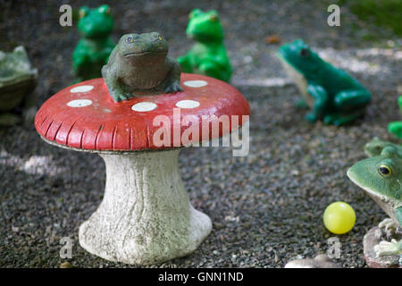 Statue von einer Kröte sitzt oben auf einem Fliegenpilz Pilz Stockfoto