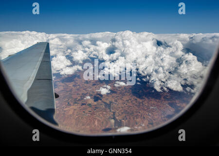 Flugzeugflügel während fliegen über den Wolken durch das Fenster gesehen Stockfoto