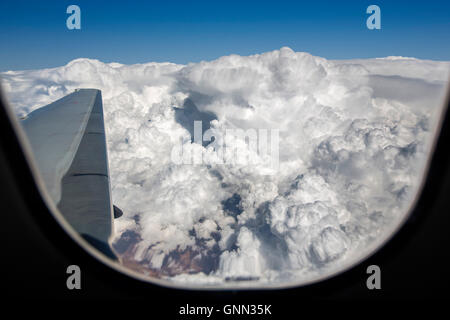 Flugzeugflügel während fliegen über den Wolken durch das Fenster gesehen Stockfoto