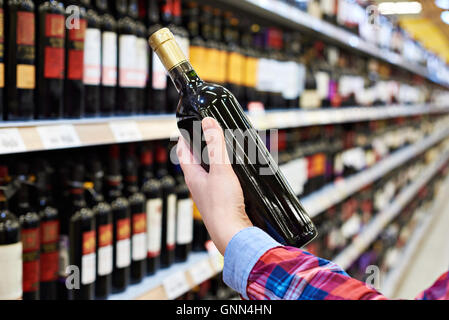 Frau mit Flasche Wein im store Stockfoto