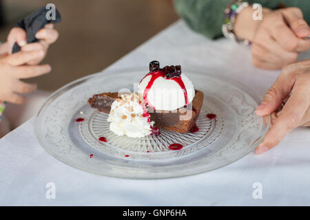 Stück Schokoladenkuchen mit Vanille-Eis, Erdbeer-Marmelade, rote Beeren-Früchten, Schlagsahne und gehackte Mutter Crocanti auf cr Stockfoto