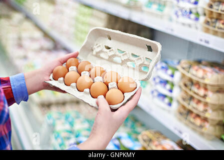 Die Verpackung in den Händen einer Frau Eiern im Supermarkt Stockfoto