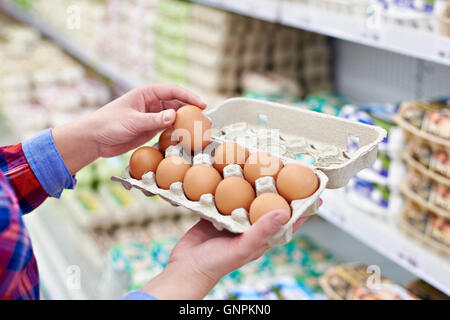 Die Verpackung in den Händen einer Frau Eiern im Supermarkt Stockfoto