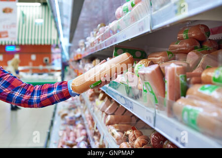 Frau wählt Würstchen im store Stockfoto