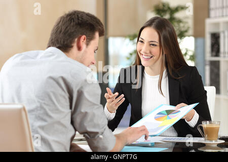 Geschäftsleute, die lächelnd coworking kommentieren und zeigen Wachstum Grafik und einem Geschäftsgespräch in einem Büro innen Stockfoto