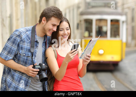 Paar lässig Touristen consulting eine Papierführung und Gps in einem Smartphone auf Linie in der Straße der Altstadt Stockfoto