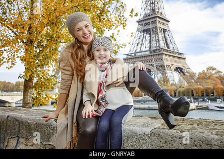 Herbst Kurzurlaube in Paris mit der Familie. Porträt der glückliche Mutter und Tochter-Reisende am Ufer in der Nähe von Eiffelturm in Paris, Frankreich auf der Brüstung sitzen Stockfoto