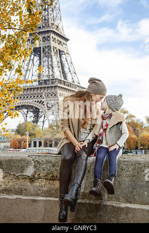 Herbst Kurzurlaube in Paris mit der Familie. In voller Länge Portrait von lächelnden Mutter und Tochter Reisende am Ufer in Paris, Frankreich auf der Brüstung sitzen Stockfoto
