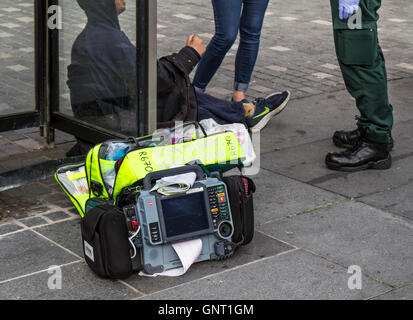 NHS Ersthelfer, der sitzende Person nach der Verwendung eines tragbaren Elektrokardiogramms in Williamson Square, Liverpool, Merseyside, Großbritannien, medizinisch behandelt Stockfoto