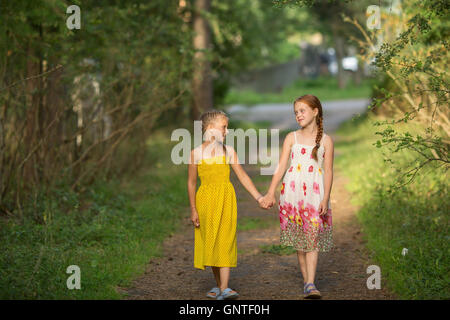 Zwei kleine Mädchen am Griff, Spaziergang durch den Park. Stockfoto