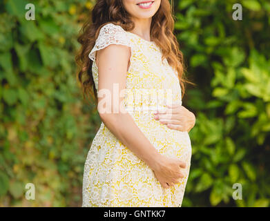 Schwangere Frau im Garten hält Bauch Stockfoto