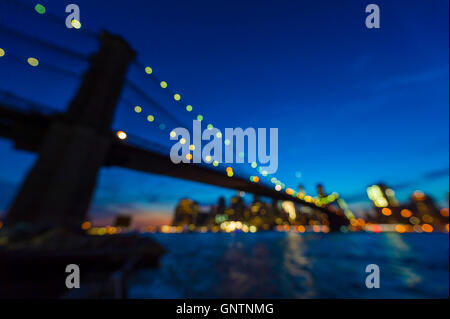 Die Skyline von New York mit Brooklyn Bridge und Downtown Manhattan aus malerischen Blick auf den Sonnenuntergang über den East River defocus Stockfoto