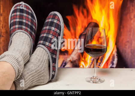 Entspannen in Pantoffeln am Kamin weißen Tisch mit Rotwein Stockfoto