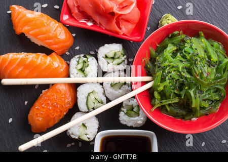 Sushi und Brötchen mit rot und Sauce auf einem Schiefer Tisch. Stockfoto