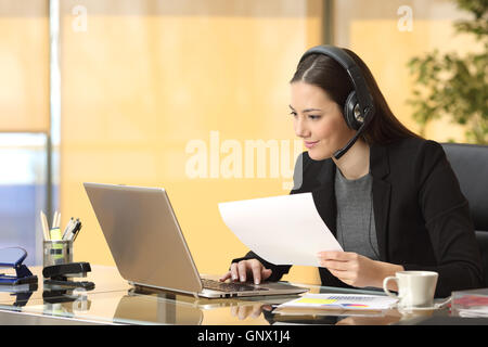 Freiberuflicher Operator online arbeiten mit einem Laptop und Headsets und halten ein Dokument im Büro Stockfoto