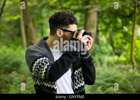 Porträt des Mannes Landschaft fotografieren mit einer DSLR-Kamera in einem Wald. Kaukasische Fotograf Außenaufnahmen mit Digitalkamera. Stockfoto