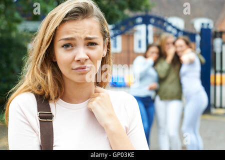 Unglückliche Mädchen wird durch Schulfreunde über geplaudert Stockfoto