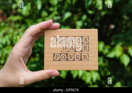 Frau Hand mit Pappkarte mit Satz Worte haben macht von schwarzen Alphabet Stempel gegenüber grünen Blumen Hintergrund gemacht. Stockfoto