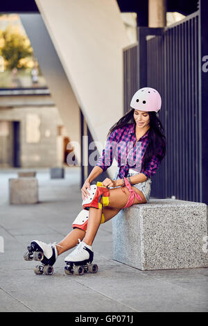 Schönes Mädchen setzt auf Schutzbekleidung für Inline-Skating Stockfoto