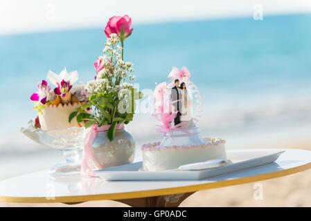 Tischdekoration für Hochzeit, Hochzeitstorte mit Puppe Mi, rosa Rosen in Vase, Gewürz-Frucht. Stockfoto