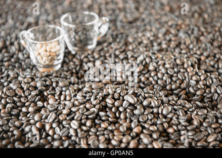 Geröstete Kaffeebohnen mit verschwommenen 2 Kaffeetassen auf Hintergrund. Stockfoto