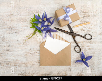 Geschenk-Box, blaue Blumen und Umschlag mit Grußkarte an die lackierten Holzplatte Stockfoto