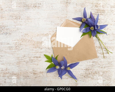 Kraft Papierumschlag mit weiße leere Karte und blaue Clematis Alpina Blumen Stockfoto