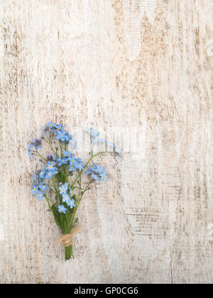 Blaue Vergissmeinnicht Blumen Bündel gebunden mit Jute Seil auf der rustikalen weiße strukturierte Holz Hintergrund Stockfoto