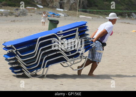 Man zieht Strandliegen am Strand Potistika, Pelion, Griechenland. Stockfoto