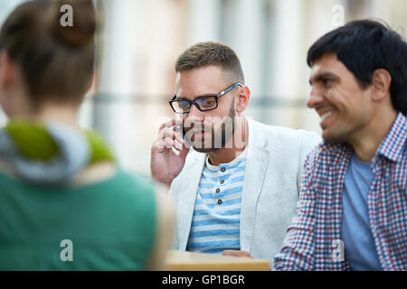 Junge Unternehmer sprechen am Telefon unter seinen Kollegen Stockfoto