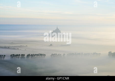 LUFTAUFNAHME. Der Mont Saint-Michel wurde gegen den frühen Morgennebel geschildet. Manche, Normandie, Frankreich. Stockfoto