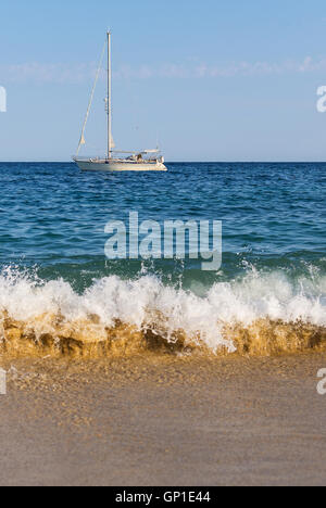 Eine schöne weiße Segelyacht auf den Wellen. Boot, Meer, Sand und Wellen. Konzept für den Tourismus. Segelschiff auf dem Wasser. Yachting. Stockfoto