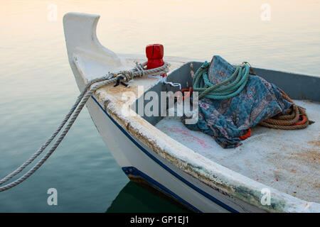 Altes Fischerboot im Morgengrauen angedockt. Kleines Holzboot am Wasser Flut mit Seilen. Sonnenaufgang in den Hafen und das Meer der Ruhe. Stockfoto