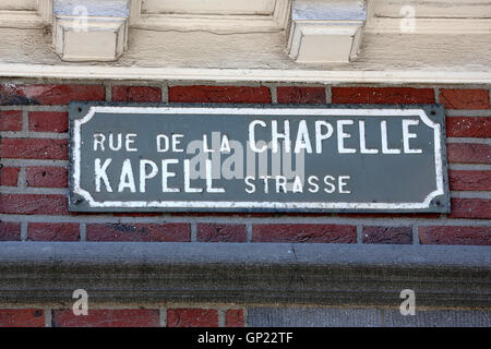 Zweisprachige Straßenschilder (Deutsch und Französisch) am Straßenrand neben einem Kruzifix in der Nähe von Kelmis/Belgien in der deutschsprachigen Gemeinschaft in Belgien Stockfoto